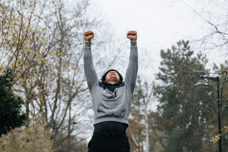 Athletic Performance The Art of Winning. A man practices his gymnastics skills and celebrates his winning performance with a confident hands up pose.の写真素材