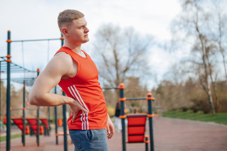 Man Down Young Adult Experiences Back Pain During Intense Sporting Activity. A Caucasian man experiencing backache while engaging in sporting activities in the great outdoors.の写真素材
