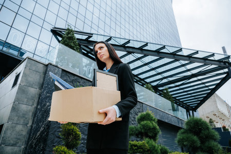 Depressed White Collar Worker After Work Loss. An unemployed person holds a cardboard box, looking worried and stressed after being fired from their job.の写真素材