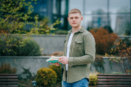 This portrait of a male sitting with his book in an outdoor location captures his lovely and authentic expression. Urban Elegance Portrait of a Young Adult Male Sitting with Book Outdoorsの写真素材
