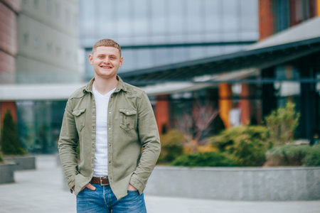 lovely and smiling young man perfectly captures the happy and satisfied emotions of the moment. His blond hair and youthful appearance while the urban outdoor setting providesの写真素材