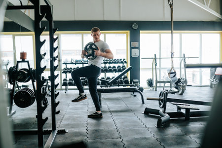 A young man showcases his strength and dedication to fitness through a weightlifting workout in the gym. Athlete with unwavering determination, engaged in a rigorous weightlifting training at the gymの写真素材