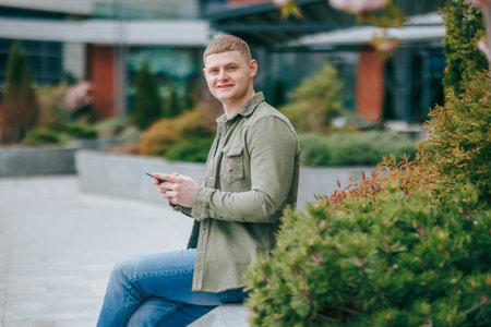 Confident young man smiling at the camera in urban setting. Young and Confident A Smiling Blond Guy in the City. City Vibes A Young Mans Urban Adventureの写真素材