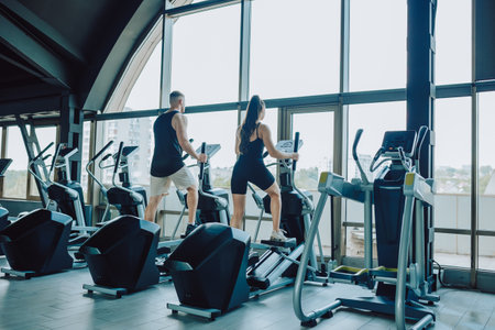 back view Hispanic man and Caucasian woman engaging in a challenging strength training workout at the gym. Hispanic and American Couple Embracing Fitness in the Gymの写真素材