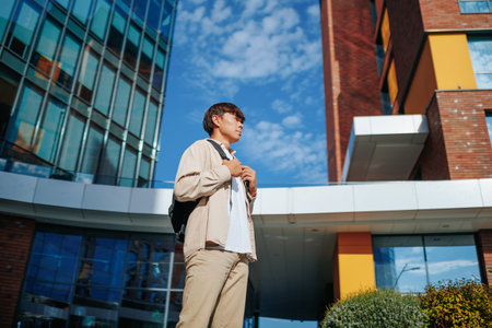 side view In the open air of the college campus, an Asian teenager, schoolbag within reach, passionately dedicates himself to his education, capturing the essence of youthful determination.の写真素材