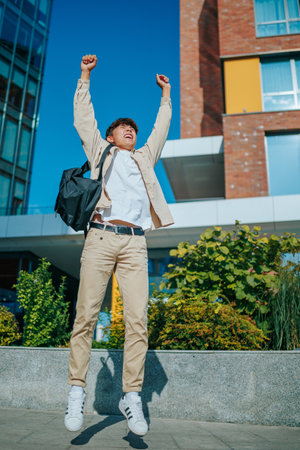 vertical portrait tells the story of a victorious Asian Korean student boy, celebrating his success outdoors with a jump of pure joy, against the stunning backdrop of an architectural masterpiece,の写真素材