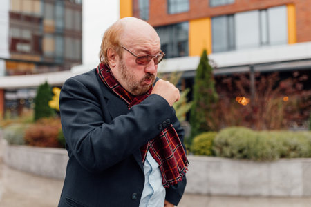 Ailing Senior with a Beard, exhibiting severe Flu Symptoms and suffering from fatigue due to seasonal influenza, displaying healthcare struggles.の写真素材