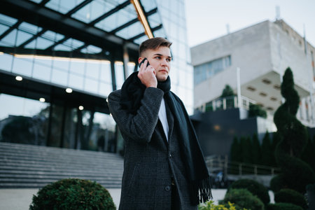 Portrait of a young American businessman with a cellphone, exuding confidence and modernity against the dynamic backdrop of city streets, a symbol of contemporary professionalism.の写真素材
