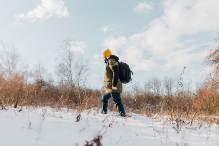 Witness the captivating journey of a Caucasian hiker walk, immersed in nature during a wintertime trek through the snow, a testament to the allure of winter exploration. side viewの写真素材