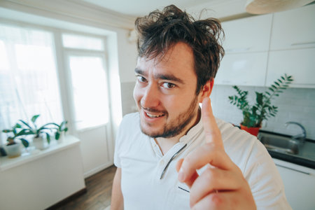 Cheerful Charm Close up portrait of a bearded man, exuding humor and joy, playfully pointing his finger up, inviting laughter.の写真素材