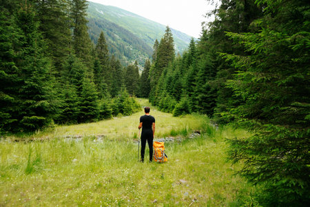 A front view of a young hiker walking through a high-elevation forest, carrying a rucksack, depicting the active lifestyle and freedom associated with trekking.の写真素材