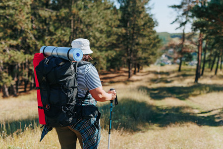 Capturing the elegance of a solo journey, this photo highlights the back view of a female backpacker navigating through nature, embodying the beauty of overweight trip adventures.の写真素材