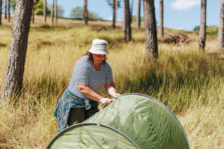 Setting Up Serenity Plus Size Woman Creates Tranquil Campsite, Arranging the Tent on a Woodland Hiking Expedition, Serenade of the Tent Plus Size Female Hiker Creates a Cozy Shelterの写真素材