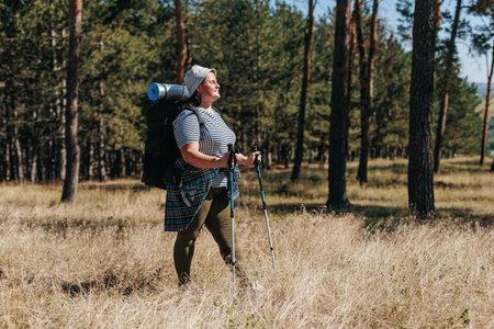 Join a solo sojourn through the scenic wilderness as a plus-size American woman takes inspiring strides on her walking expedition. Immerse yourself in the beauty of her journey,の写真素材