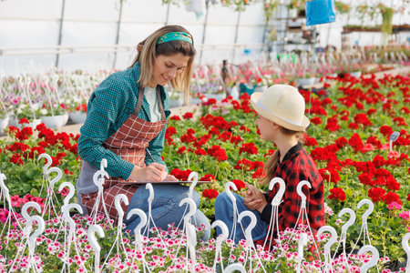 study and next generation, woman and child busines familiar with greenhouse plants. the child makes notes in the notebook, meanwhile mom helps her learn floristics. copy spaceの写真素材