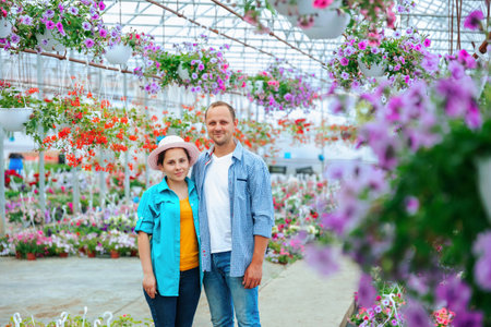 A family of aspiring flower sellers stands in a greenhouse, then turn and look at the camera. The couple is happy, with a triumphant smile on their faces. Copy spaceの写真素材
