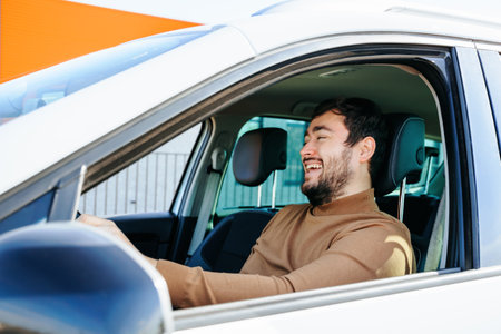 A middle aged man smiles happily while driving his car. The young man loves to drive a vehicle. The concept of happiness. Good life events make you rejoice.の写真素材