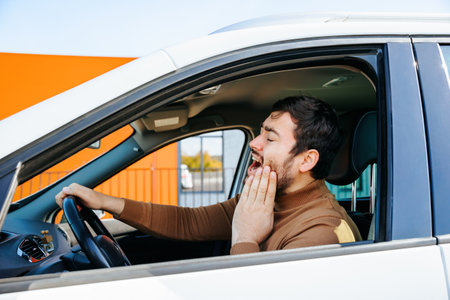 hispanic bearded man chauffeur with toothache in vehicle at the wheel and pain, he is mad. nice, the young man has negative emotions dental pain, his hand on faceの写真素材