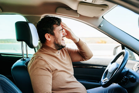 Young guy male with closed eyes, open mouth and beard. The driver sits in the car and suffers from headaches and neuralgia. Expressive facial expression.の写真素材
