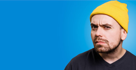 A man with suspicion and uncertainty in a studio portrait. his mind is evidently troubled, and his body language shows that he is worried. The studio shot, copy spaceの写真素材