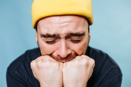 close up portrait of people, one of them an angry male with eyes closed, as they look directly at the camera and express their emotions. studio shot on the blue background,の写真素材