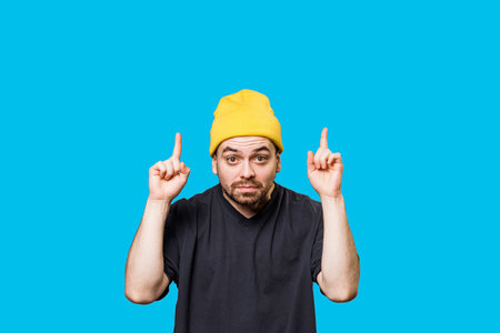 A portrait of a people caucasian man in this studio shot, grimacing with a bizarre expression while pointing to free space, looking directly at the camera and providing ample copy space.の写真素材