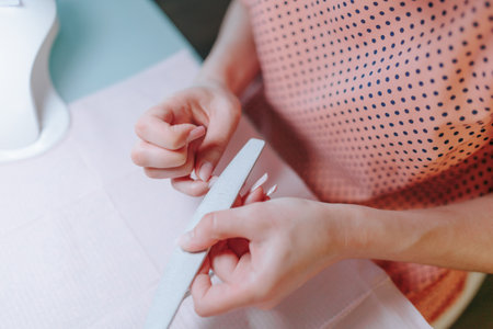 With unwavering focus, a woman manicurist meticulously works on her nails at home, embodying the essence of self-care and personal grooming.の写真素材