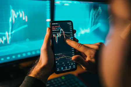 his focused hands typing away on a smartphone screen amidst a sea of charts and graphs. The mans expertise in the field of trading is reflected in his confident movements and unwavering attentionの写真素材