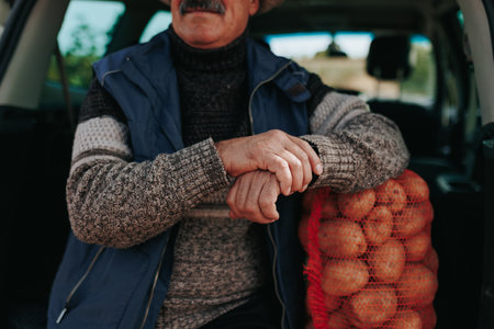 Detailed Close Up Aged farmers hands delicately arranged near a bountiful sack of freshly harvested vegetables, captured during the harvest season.の写真素材
