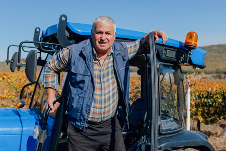of the countryside, a senior male farmer exudes confidence and pride as he stands beside his tractor, a vital tool in his daily labor of nurturing the earth and reaping its rewards.の写真素材