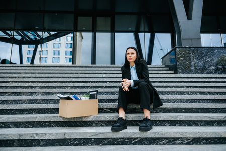 Unemployed and Alone A Woman Sitting on Stairs with a Cardboard Boxの写真素材