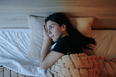Relaxed Woman Getting Ready for Sleep in a Comfortable Bedroom Settingの写真素材