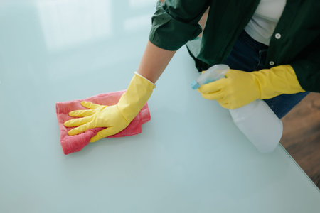 Close Up of a Woman Hands with Yellow Gloves Cleaning the Kitchen Table at Home