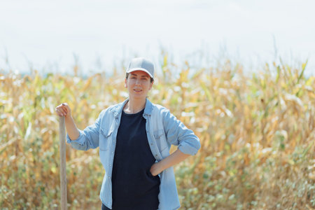 Portrait of a Woman in a Cap and Denim Shirt Standing in a Cornfield