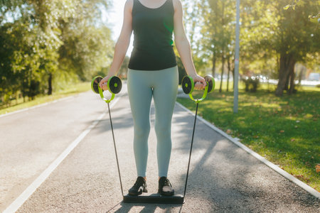 Young white woman performs resistance band exercises in the park on a sunny dayの写真素材