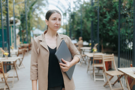 Modern Businesswoman Holding Laptop on Outdoor City Terraceの写真素材