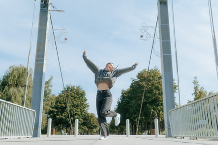 Happy teen girl leaps into the air in the park, carefree and smiling.の写真素材