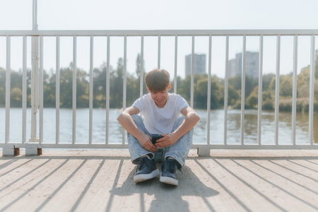 Carefree Young Boy Relaxing with Mobile Phone, Enjoying Online Lifeの写真素材