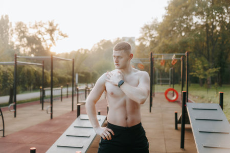 Young male athlete with naked torso standing outdoors post-workout.
