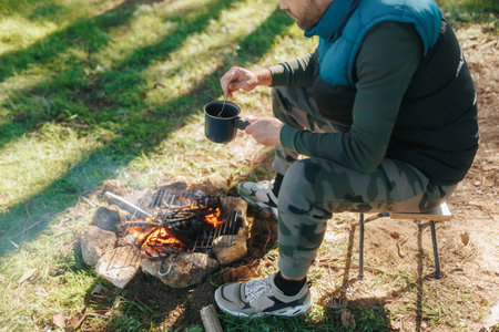 Preparing a Warm Meal by the Campfire in a Scenic Forestの写真素材
