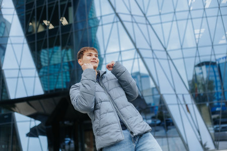 Happy teenage boy celebrating in the city, joyful expression on urban backdropの写真素材