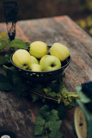 Bowl of green apples sits on a wooden tableの写真素材