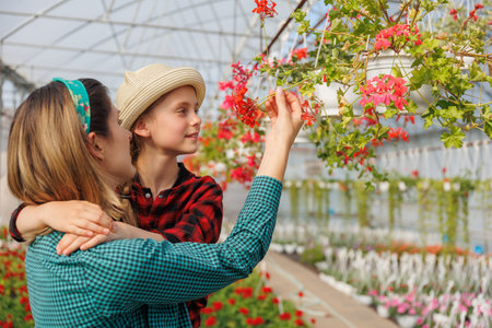 pretty mother and child daughter watching analyze flowers in greenhouse.の写真素材