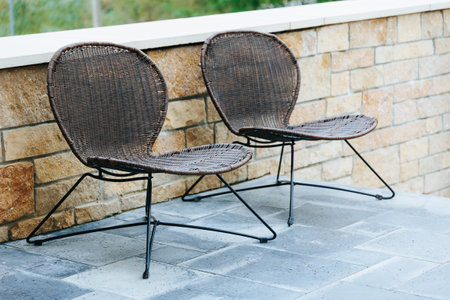 Wicker chairs with black metal frames on a patio, ideal for outdoor relaxation.の写真素材