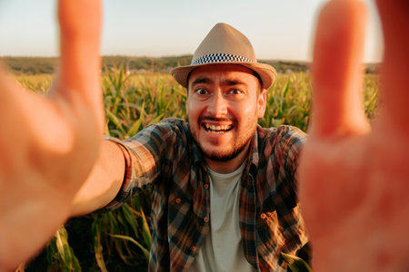 Farmer enjoys sunny day in cornfield while reaching out with a smileの写真素材