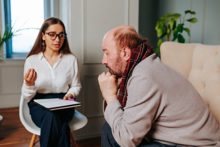 Man in thoughtful discussion with a therapist in a modern office settingの写真素材