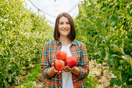 Woman holding freshly picked apples in an orchard during harvest season