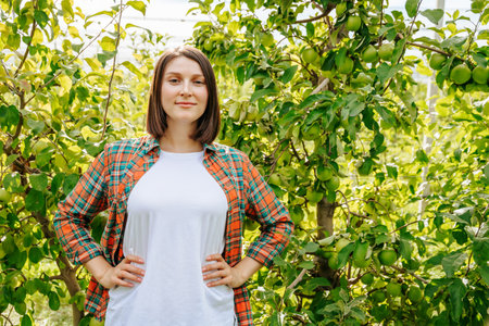 Confident woman standing among apple trees on a sunny afternoonの写真素材