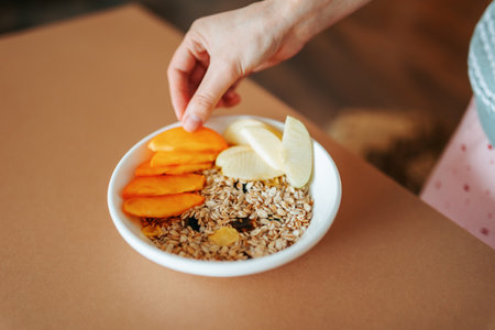 Healthy breakfast preparation with fresh fruits and oats in a cozy kitchenの写真素材
