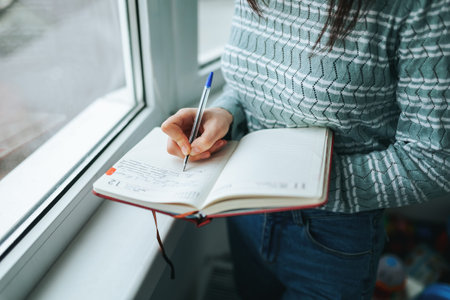 Writing in a notebook by the window on a rainy day